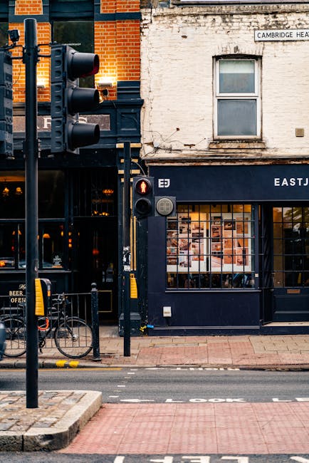 The image depicts a street scene outside a vintage-style building with a dark navy blue façade, housing a florist shop. The storefront features large glass windows displaying various floral arrangeme