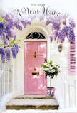 This scene captures a tender new-beginnings moment on a quiet Cambridge Heath street, where a pastel pink front door becomes the focal point beneath a draping canopy of lavender wisteria. The wisteria cascades in soft, fragrant clusters from above, creating a natural archway that frames the doorway much like the leafy stretches along nearby London Fields. The door's blush pink paint is calm and inviting, standing out gently against the whitewashed wall and a lightly coloured shutter that both reflect the soft daylight. Resting on the doorstep is a grey metal bucket, sturdy yet stylish, brimming with a hand-arranged display of white and cream roses. The roses are full and velvety, their rounded heads nudging closely together, with accents of fresh green foliage peeking out to break up the light tones and add depth. A satin ribbon in a delicate pink hue is tied around the bucket, the bow's tails slipping gracefully over the edge and across the worn stone step, mirroring the shades of the door and binding the composition into a single, pastel story. Gentle sunlight filters through the wisteria vines, casting flickering shadows over the roses, door, and wall, so that everything appears bathed in a warm, late-afternoon glow. The atmosphere feels warm, sheltered, and full of promise, as though this arrangement has been placed by someone eager to wish the new occupants joy, comfort, and good fortune in their Cambridge Heath home. It is a visual and emotional welcome, captured in flowers and soft colour.